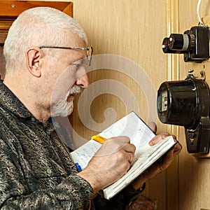 A man records the readings of an electricity meter