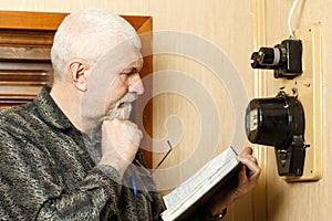 A man records the readings of an electricity meter