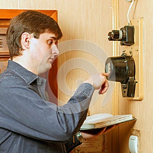 A man records the readings of an electricity meter