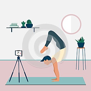 A man records a yoga video tutorial on his smartphone. A young man standing in the scorpion handstand pose Vrschikasana