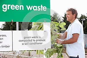 Man At Recycling Centre Disposing Of Garden Waste