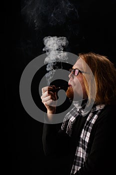 Man with red beard in chequered scarf and glasses holds tobacco