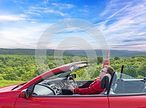 Man in red car with open roof at background of sea water.