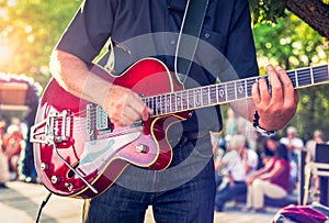 Man with a red electric guitar in the park playing a concert