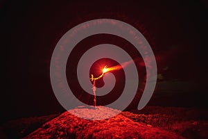 The man with a red firework stick standing on a mountain. evening night time.