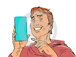 A man with red hair smiles and points to the phone. Product demonstration or offer on smartphone. The joy of a perfect