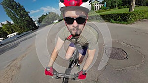 Man in red helmet and red gloves ride on bicycle. Tracking shot