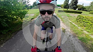 Man in red helmet and red gloves ride on bicycle. Tracking shot