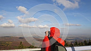Man in Red Hood in Mountains Looking through Binocular Outdoors
