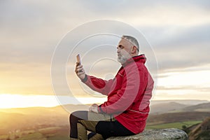 Man in red jacket relaxing alone on the top of mountain at sunrise. Travel Lifestyle concept The national park Peak
