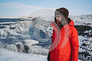 A man in a red jacket stands near the largest waterfall in Iceland, Gullfoss. The most beautiful and popular attractions in Icelan