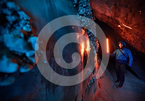 Man with red lamp in amazing blue ice cave