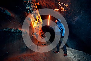 Man with red lamp in amazing blue ice cave