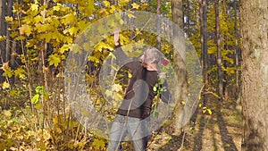 Man with red roses waiting for his beloved woman on a date in the autumn forest