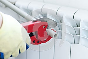 Man with red scissors cut pipes for heating, or water. polypropylene mounting system