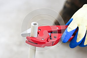 Man with red scissors cut pipes for heating, or water. polypropylene mounting system