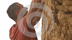 A man in a red shirt is climbing a rock wall