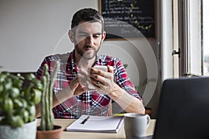 Man in red shirt using cellphone in home office