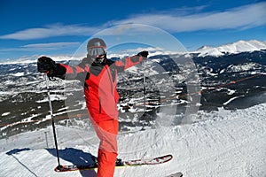 Man in red ski suit standing on the top of Breckenridge ski resort.