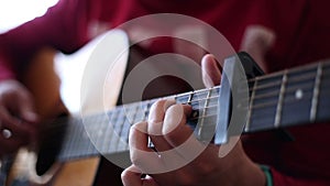 A man in a red sweater plays an acoustic guitar indoors a close-up view of an wide open aperture