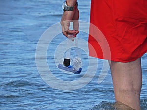 Man in Red Swimming Shorts Holding Diving Mask in his Hand while Standing in Water