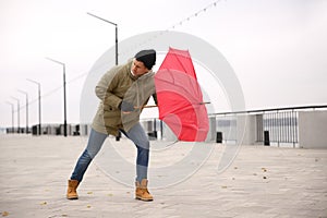 Man with red umbrella caught in gust of wind outdoors