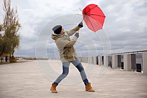 Man with red umbrella caught in gust of wind outdoors