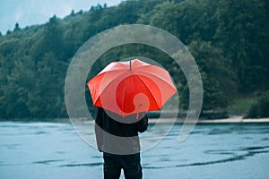 Man with red umbrella contemplates on rain