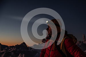 Man in red winter jacket at the way to mountain top at winter.