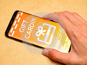 Man redeeming a generic gift card voucher on his smartphone, receiving a coupon code in app, mobile phone, hand closeup