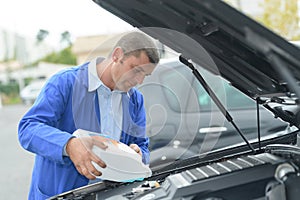 Man refilling vehicle with screen wash