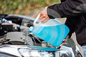 Man refills windshield wiper water on a car