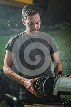 Man refitting a lawnmower wheel photo