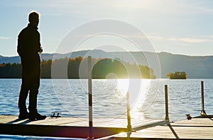 Man reflects on dock during Autumn on Memphremagog Lake, Quebec, Canada