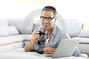 Man with reflex camera and laptop at home