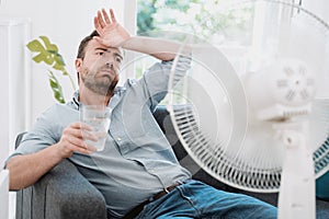 Man refreshing with electric fan against summer heat wave