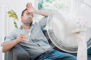 Man refreshing with electric fan against summer heat wave photo