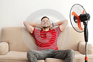 Man refreshing from heat in front of fan