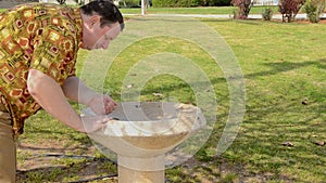 Man refreshing his face with drinking fountain