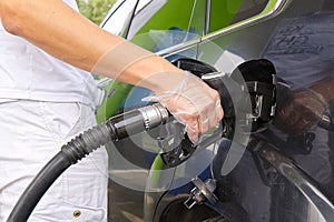 A man refueling a black car with diesel fuel at a gas station. Refueling nozzle close up and jet of fuel.