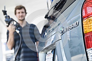 Man Refueling Blurred Hybrid Car