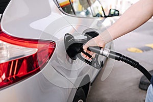 Man refueling the car at a gas station. Close-up of driver hand pumping gasoline car with fuel at the refuel station.