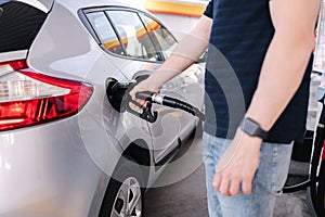 Man refueling the car at a gas station. Close-up of driver hand pumping gasoline car with fuel at the refuel station.