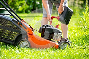 Man refueling the lawnmower on his huge garden, gardening concept