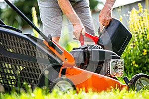 Man refueling the lawnmower on his huge garden, gardening concept