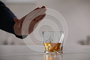 Man refusing to drink whiskey indoors, closeup. Alcohol addiction treatment