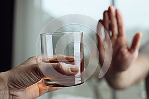 Man refusing to drink whiskey indoors, closeup. Alcohol addiction treatment