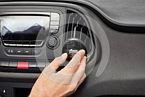 Man regulating air freshener near ventilation in car