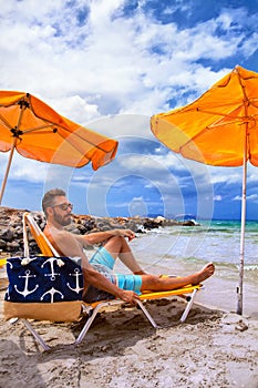 Man relax on the beach in a chair under umbrella