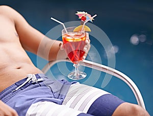 Man, relax and drink at swimming pool with cocktail at hotel, resort and travel on luxury vacation. Summer, holiday and